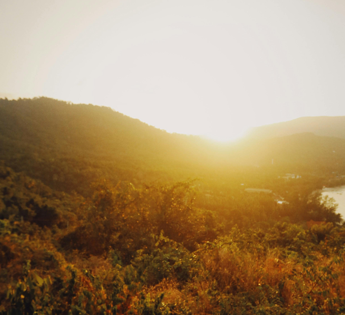 Sunrise in a lush, treelined, hilly landscape with a warm golden glow and a serene river, representing untold opportunities.