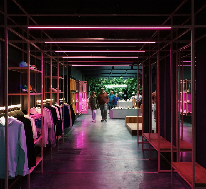 Clothing in a room with pink neon lights, symbolizing a leisurewear company moving to wholesale and growing their business.